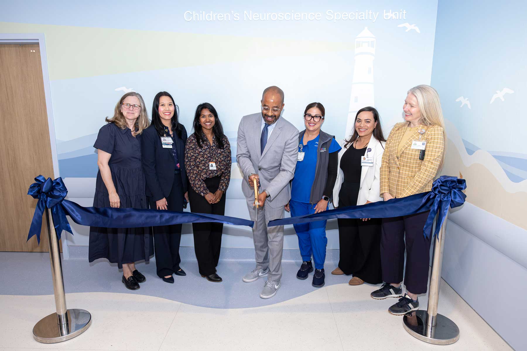 Nicholas Holmes cuts a blue ceremonial ribbon alongside clinicians and staff to celebrate the opening of the Children's Neuroscience Specialty Unit.