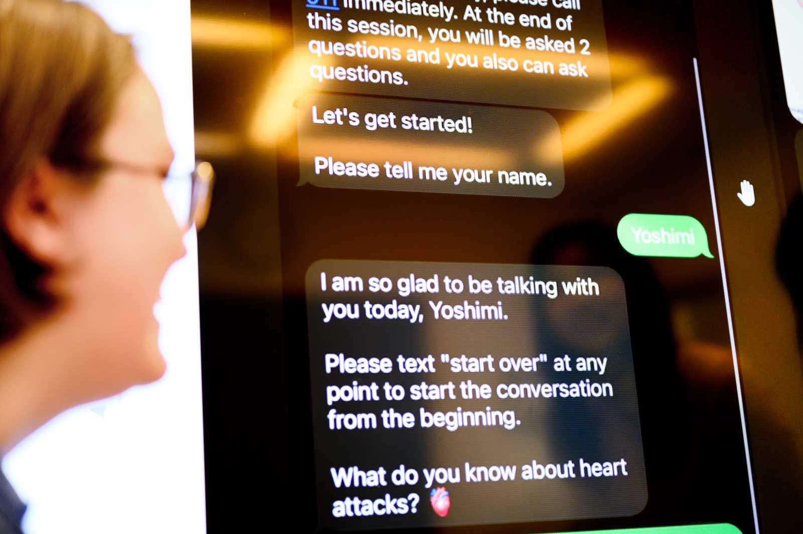 A clinical research croodinator smiles in the foreground and in the background is a screen of a chatbot.