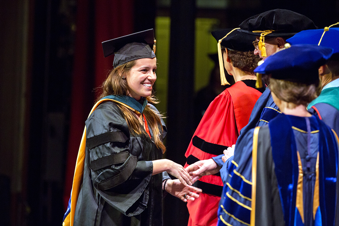 Carolina Zubiri shakes hands with UCSF Chancellor Sam Hawgood, MBBS, and deans after receiving her Doctorate of Physical Therapy degree during the Graduate Division commencement ceremony.