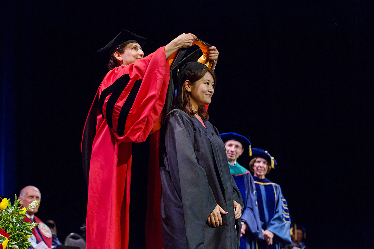 r of SElizabeth Watkins, PhD, dean of the Graduate Division and vice chancellotudent Academic Affairs, places a hood on a graduate student during the Graduate Division commencement ceremony.