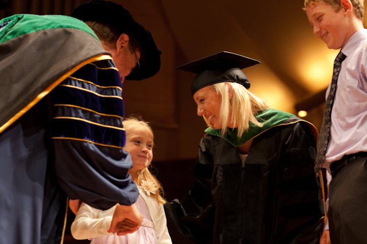 A girl is greeted by Dean Hawgood after her mother is hooded as a new graduate of the School of Medicine.