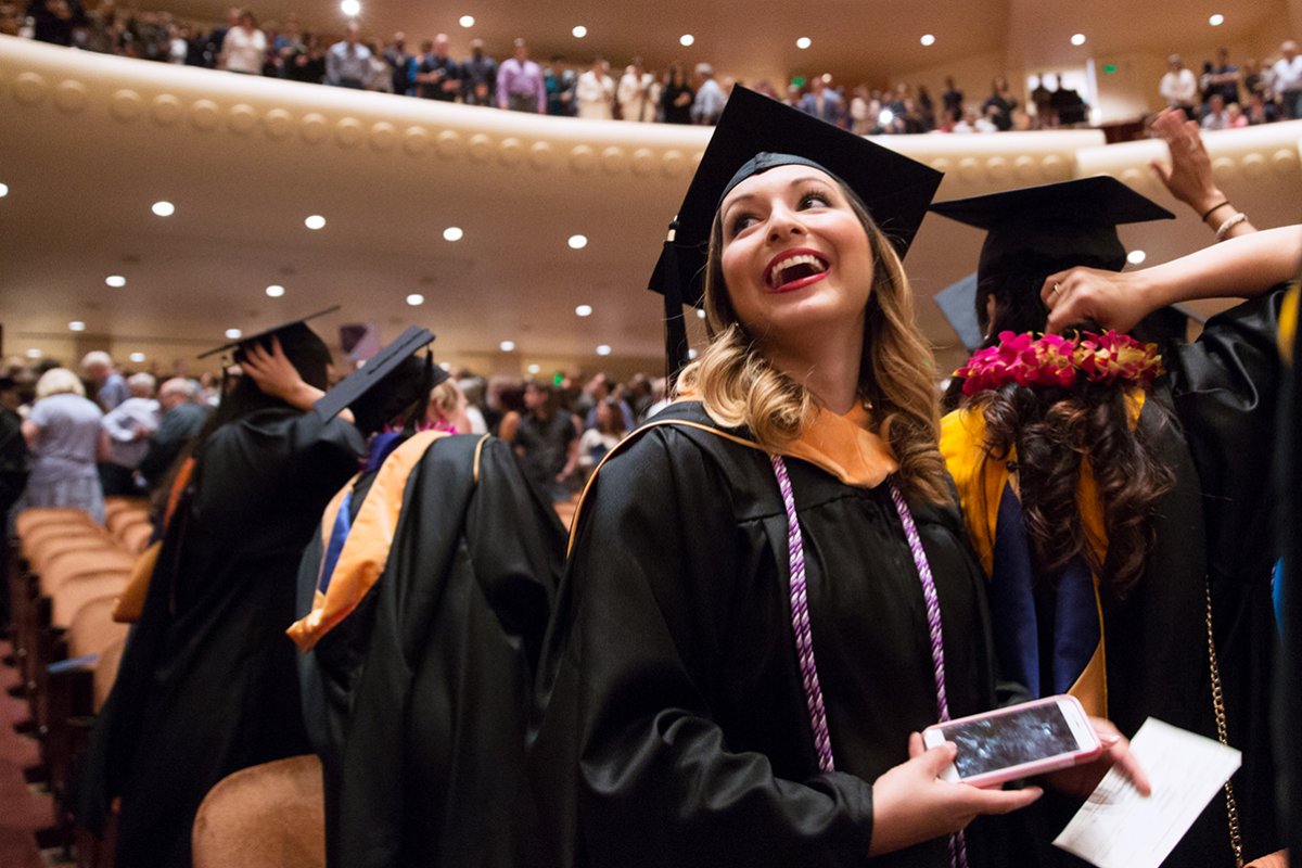 A UCSF School of Nursing graduate celebrates during the commencement.