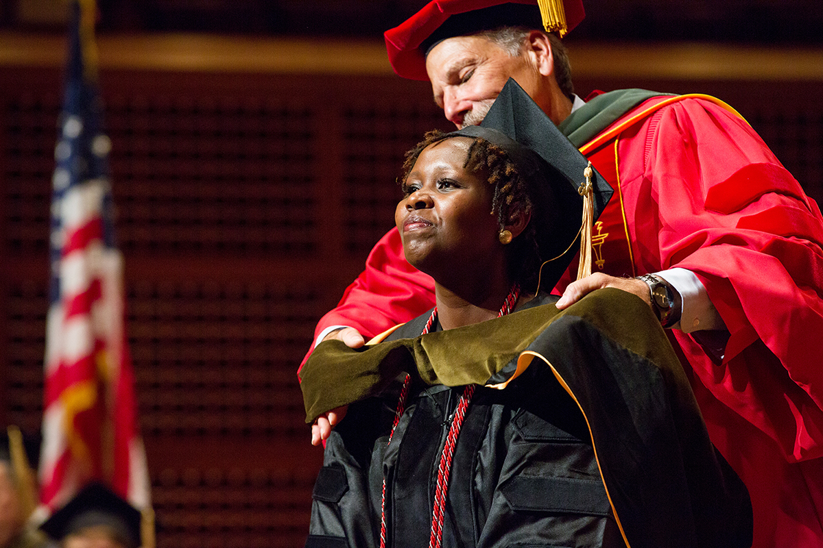 School of Pharmacy Dean B. Joseph Guglielmo places a doctoral hood over the head of Jackline Githinji, signifying her completion of the PharmD program, during the school's commencement on May 5 at Davies Symphony Hall.
