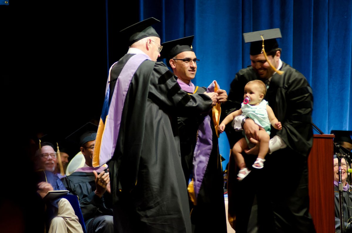 student holding baby at the graduation ceremony