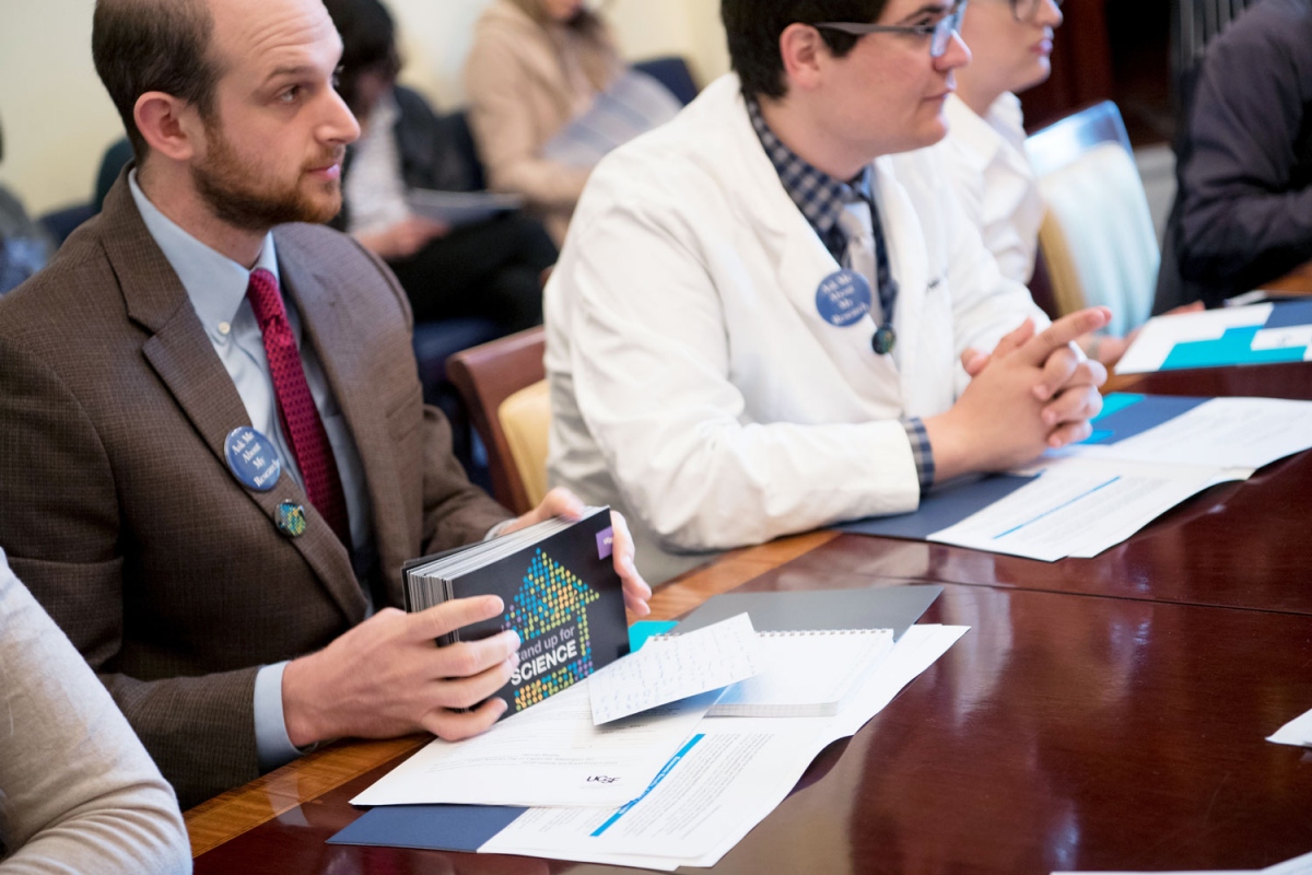 Steven Moss, a student pursuing a PhD in chemical biology, holds a large stack of postcards signed by UCSF faculty, staff, students and community members during the "Stand Up For Science" event, to be delivered to House Minority Leader Nancy Pelosi.
