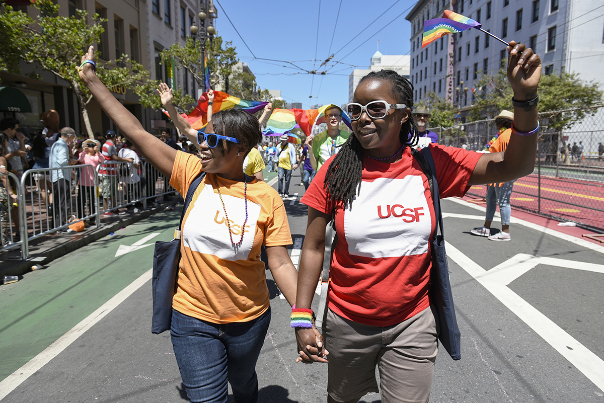 Two members of UC San Francisco's Pride Parade contingent smile and wave during the parade along Market Street.
