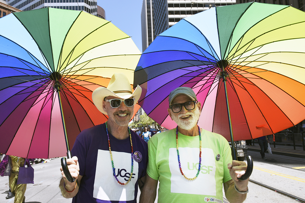 Two members of UC San Francisco's Pride Parade contingent walk with rainbow-colored umbrellas during Sunday's parade.