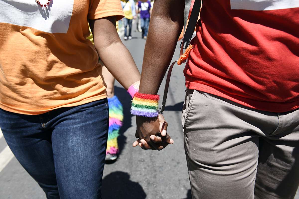 Two members of UC San Francisco's Pride Parade contingent hold hands as they walk in the parade.