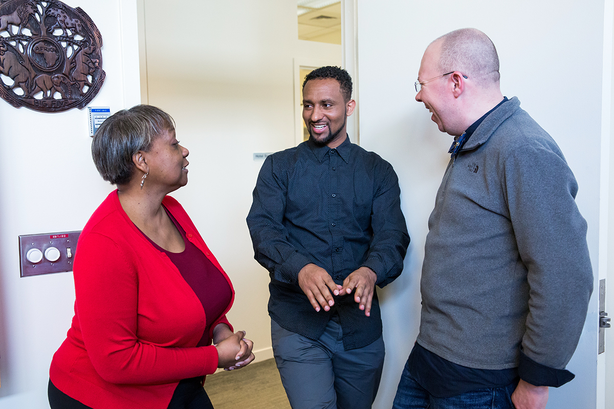Henock Woldu (center) chats with Sharon Youmans (left), PharmD, MPH, vice dean of the School of Pharmacy and professor of Clinical Pharmacy, and Marcus Ferrone (right), PharmD, JD, associate professor of Clinical Pharmacy, in the dean's office.
