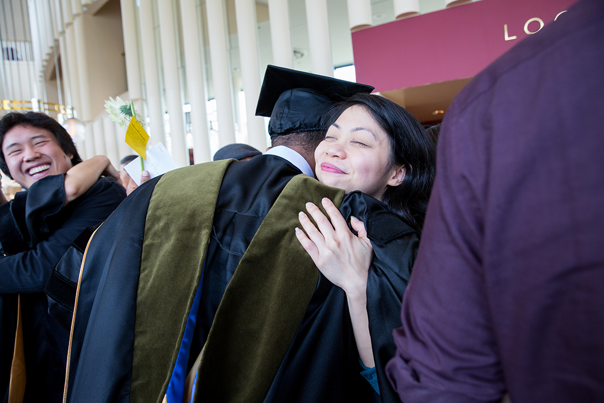 Thanh Le, a third-year student in the School of Pharmacy, hugs Henock Woldu after the commencement ceremony in Davies Symphony Hall.