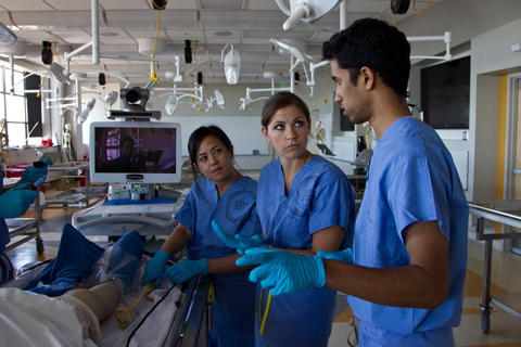 Fourth-year medical students Dominique Marie Suarez, Dora Friedman and Kanul Raygor get ready to administer an intraosseous infusion on a cadaver.