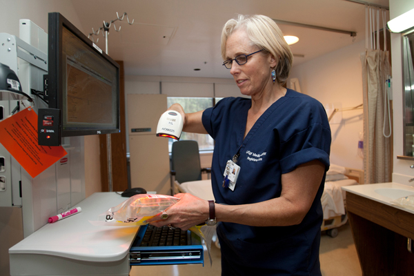 UCSF nurse Elizabeth Dunn uses a bar code scanner to chart patient medication using the new APeX system