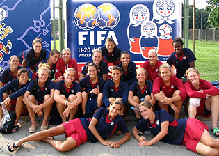 US Women's U-20 team in front of the tournament logo.