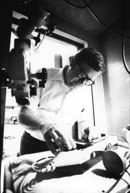 black-and-white photo of a young Michael Merzenich working on a cochlear implant