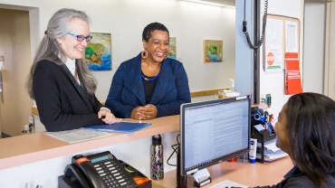 Nancy Milliken, Judy Young and Nicole Galvin talk at the front desk of the UCSF National Center of Excellence in Women's Health.