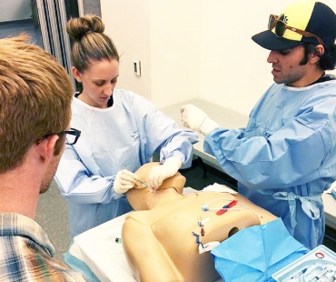 three medical students practice on the dummy