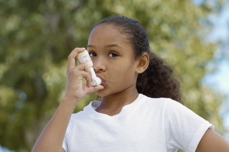 A stock image shows an African-American girl using an asthma inhaler