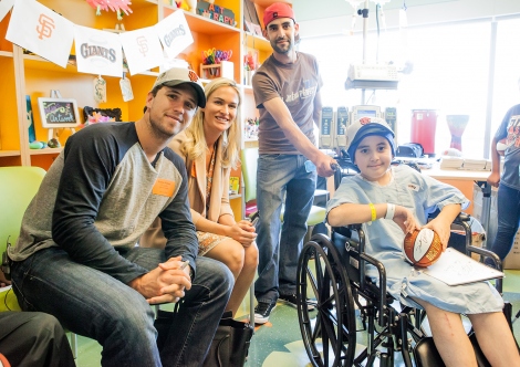 Buster Posey and Kristen Posey pose for a picture with a pediatric cancer patient during their visit to Benioff Children's Hospital San Francisco