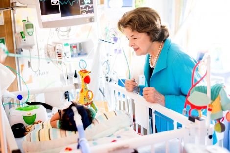 Dianne Feinstein looks into a crib with a sick child