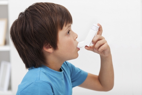 A stock image shows a young boy using an asthma inhaler
