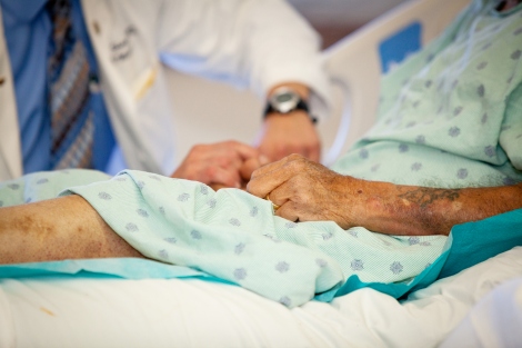 an elderly patient in a hospital bed with a doctor in the background