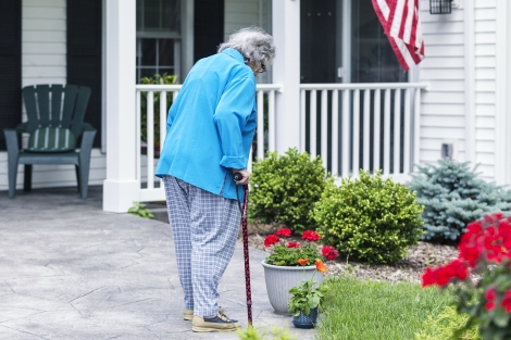 an elderly woman walks with a cane