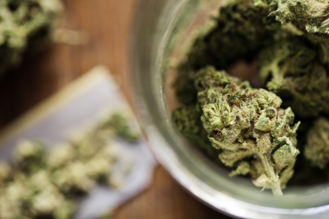 stock image of marijuana sitting in rolling paper and marijuana buds in a jar