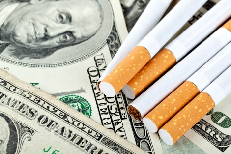 stock image of cigarettes resting on top of $100 bills