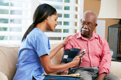 stock image of nurse taking an elderly man's blood pressure at home