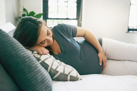 Pregnant woman resting on bed.
