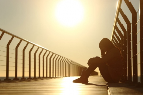 stock image of sad teen girl sitting on a bridge