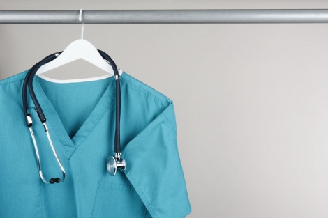 scrubs and a stethoscope on a hanger in a closet