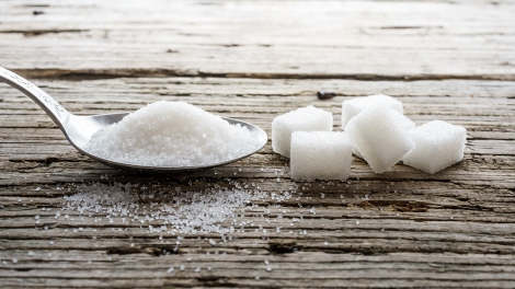 A stock image shows a spoon with sugar and sugar cubes on a table