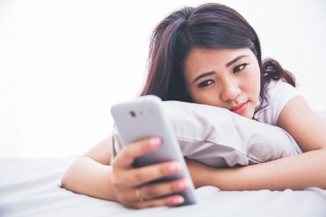 stock image of sad woman looking at her smartphone