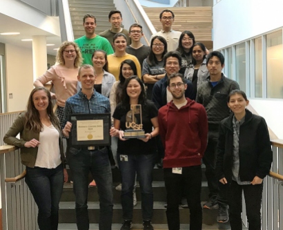 Kampmann lab members posing on stairs with award