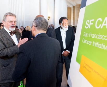 people talking next to an SF CAN sign at a City Hall event
