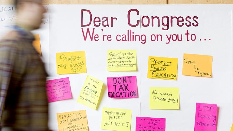 a person walks past a whiteboard with the words "Dear Congress We're calling on you to..."