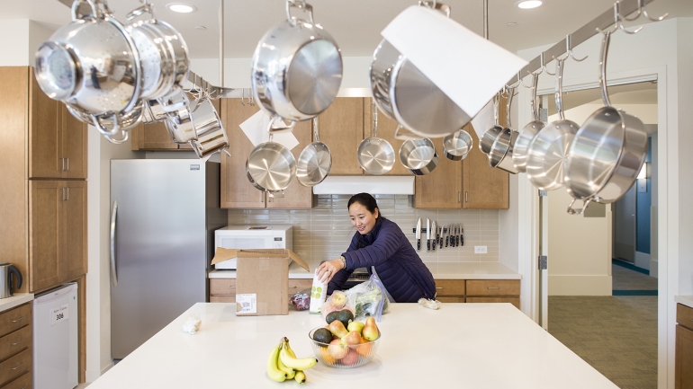 Lhamo unpacks food in a kitchen at the Family House's new home in Mission Bay