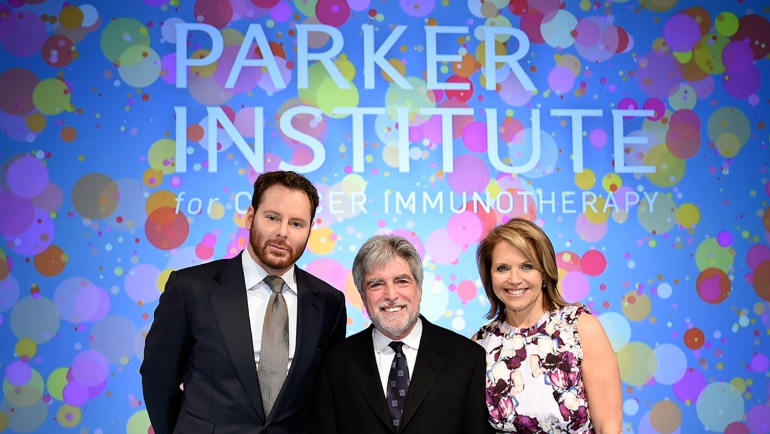 Sean Parker, UCSF immunologist Jeffrey Bluestone and journalist Katie Couric stand in front of a sign annoucing the new Parker Institute for Cancer Immunotherapy during an event in Los Angeles