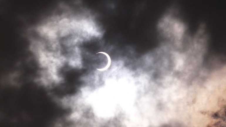 solar eclipse seen through clouds