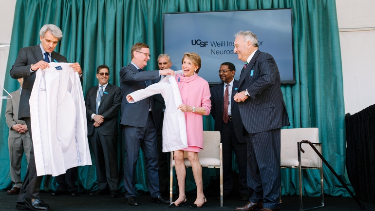 Stephen Hauser and UCSF Chancellor Sam Hawgood present Joan and Sandy Weill with white physicians’ coats 