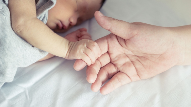 stock image of newborn holding an adult hand