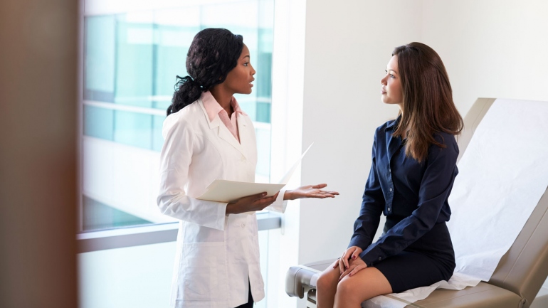 stock image of doctor talking to a female patient in an exam room