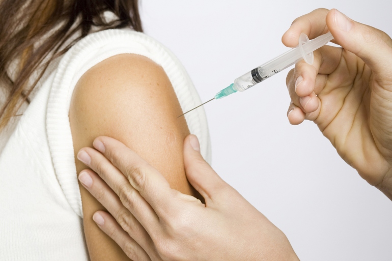 A stock image shows a woman receiving a shot