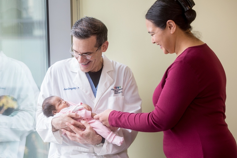 Juan Gonzalez Velez holds the baby Elianna while Nichelle Obar looks on