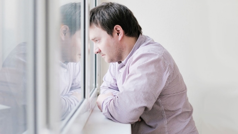 stock image of sad man looking out the window