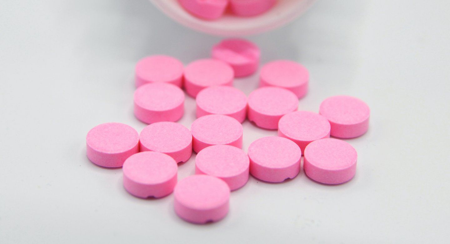 pink pills spilling out of the bottle.