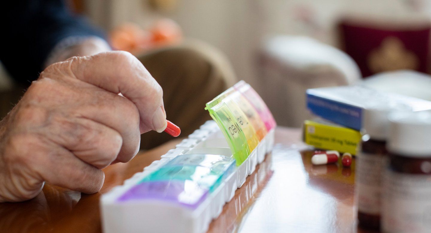 Elderly man arranging pills in a pill organizer