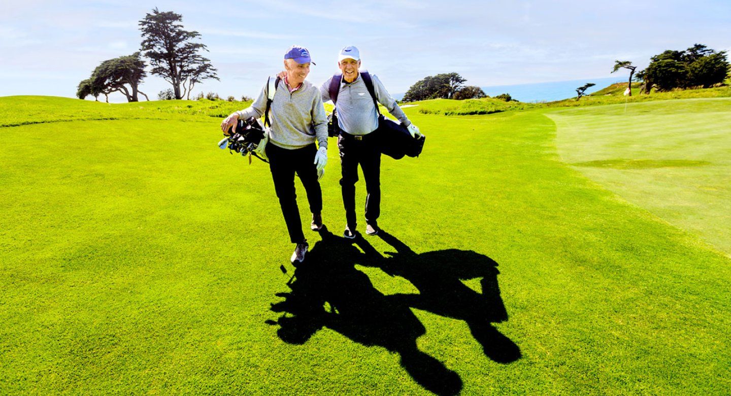 Don Onken puts a hand on his friends shoulder as they walk across the lawn of a golf course
