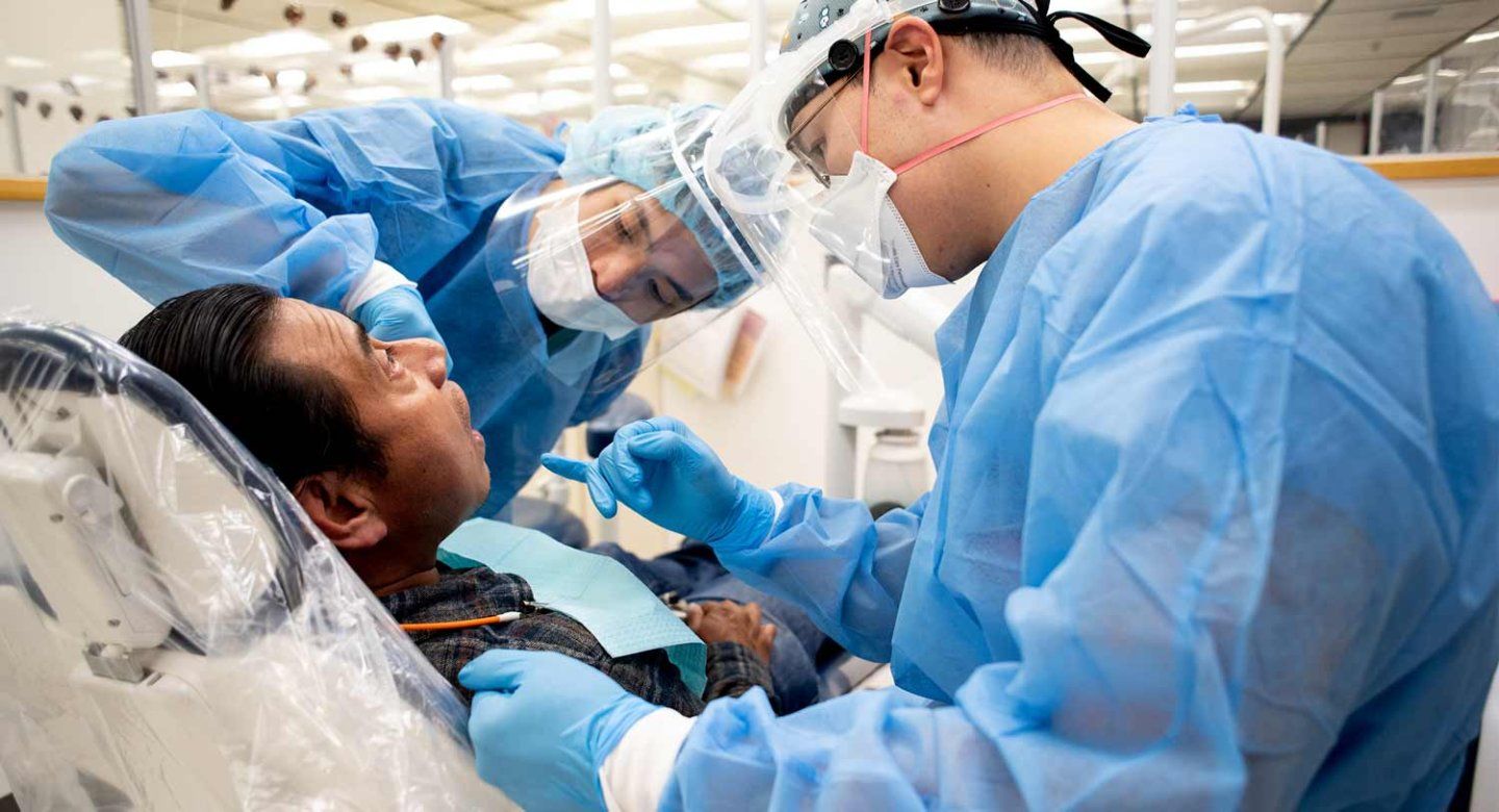 A pair of dentistry students provide dental care to a patient.